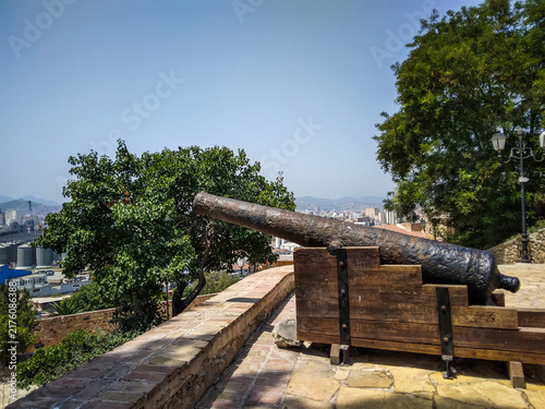 фотографія Ancient metal cannon on a sturdy wooden carriage atop a historic stone wall overlooking Béjaïa, Algeria, under a clear blue sky