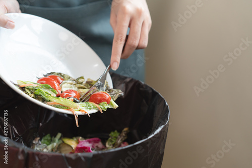Картината върху платно The housewife is throwing the leftover food from the meal into the bin