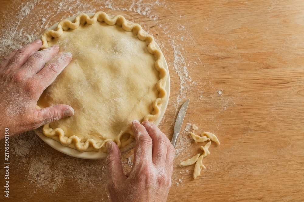 Obraz premium Hands crimping the edge of a pie in a ceramic dish