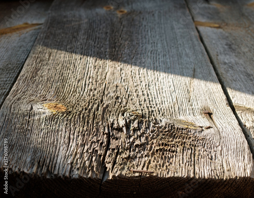 Detailed shot of old rustic wooden boards featuring deep grain and rough texture, bathed in bright natural sunlight creating a contrasting sharp shadow effect