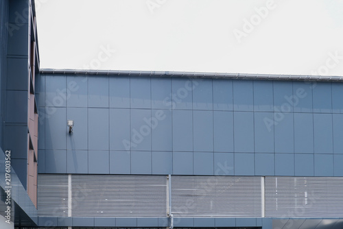 Modern Industrial Building Facade with Blue Metal Cladding Panels, CCTV Camera, and Exterior Wall Structure