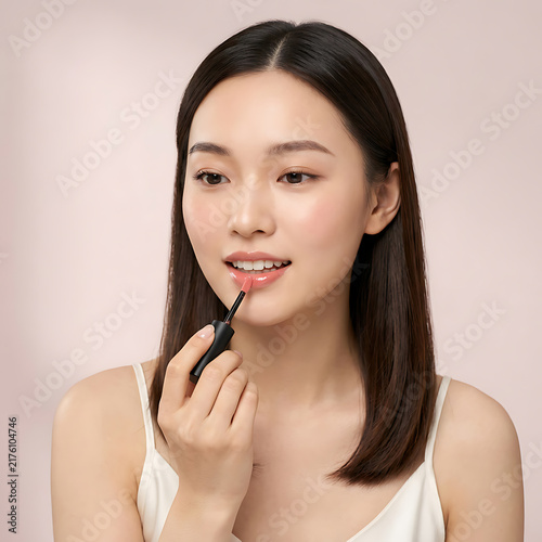 A young woman applying lipstick with a calm expression against a neutral background