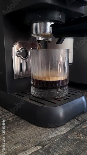 Latte coffee being brewed by a professional machine into a glass. morning energy, cafe routine, delicious creamy beverage.