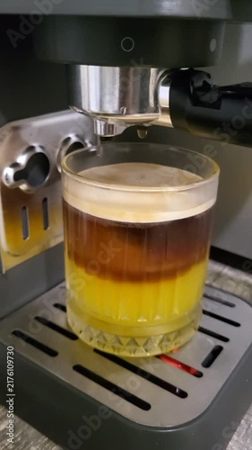Layered bumble coffee with fresh orange juice and ice cubes in a tall glass, creative summer refreshment, cool beverage, cafe lifestyle.