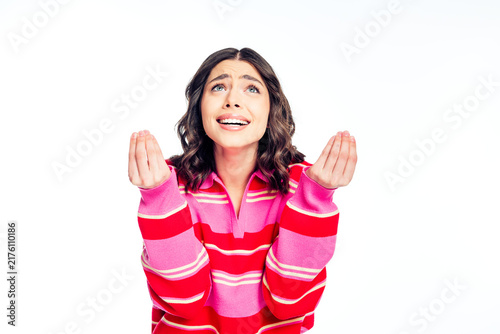 Fotografie Hopeful young woman in pink striped sweater pleading with palms up in an express