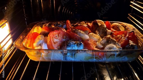 Finished roasted fish with colorful vegetables served in a glass baking dish, nutritious family dinner, gourmet home cooking, healthy lifestyle.