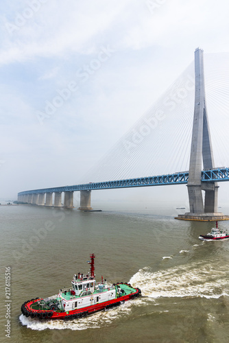 Zhangjinggao Yangtze River Bridge rising above the Yangtze River on a misty morning, photographed from a commercial vessel passing underneath.