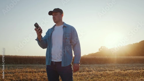 Farmer checks smartphone call during sunset walk across field