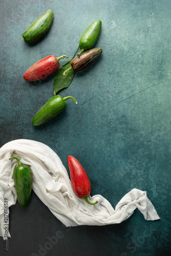 Obraz na płótnie Green and red, jalapeno chili peppers on dark green surface with a white cloth