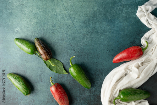 Obraz na plátne Green and red, jalapeno chili peppers on dark green background with a white cloth
