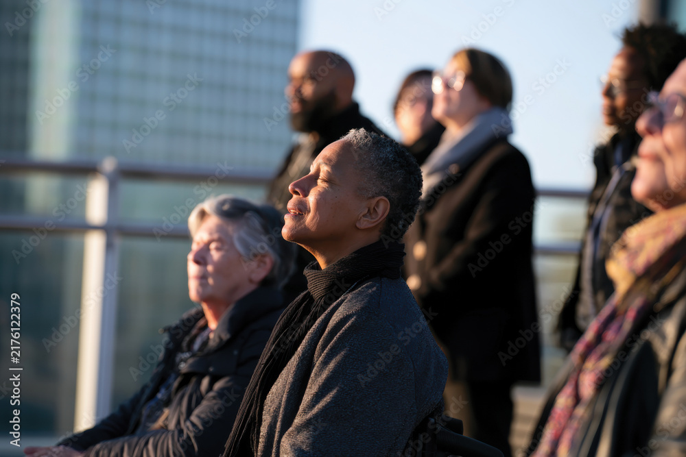 Obraz premium A diverse group of individuals embraces tranquility during sunset, signifying emotional growth, mindfulness, and the beauty of shared experiences in a serene outdoor setting.