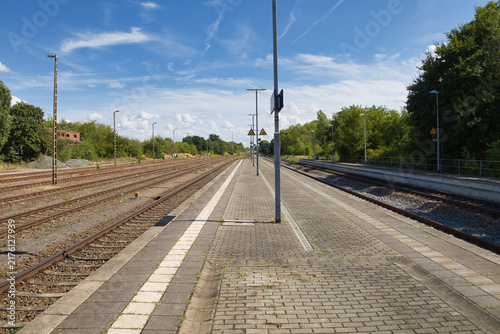 Blick über den leeren Bahnsteig und die weitläufigen Gleisanlagen des Bahnhofs an einem sonnigen Sommertag, Salzlandkreis, Sachsen-Anhalt, Deutschland