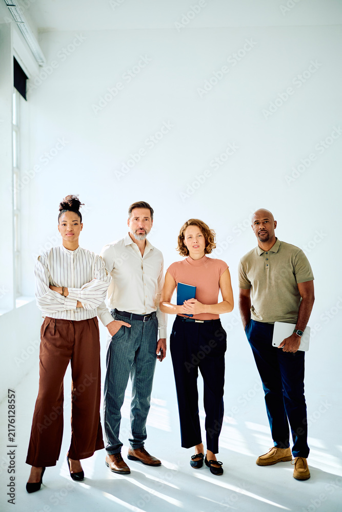 Fototapeta premium Professional multi-ethnic business team standing confidently on white background, collaborating and symbolizing unity and success