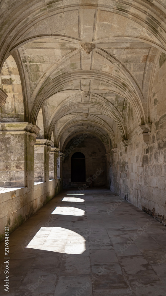 Fototapeta premium Stone cloister hallway with arches and game of light and shadows