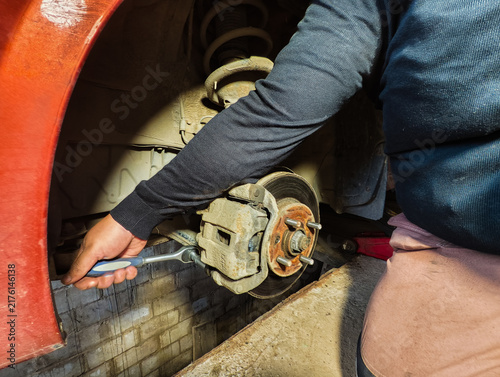 Foto Mechanic working on a vehicle's suspension and brake system, using a ratchet wre