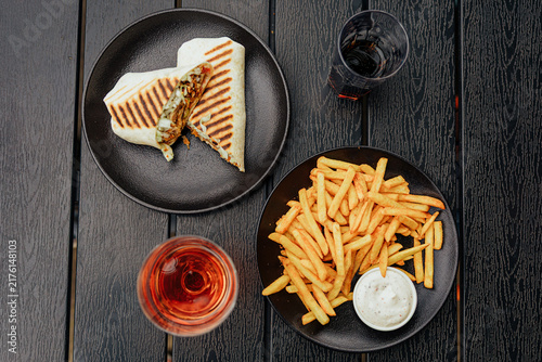 Foto Top view of a grilled wrap, seasoned French fries with creamy dipping sauce, and