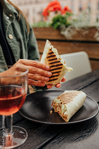 Принти на полотні Close-up of a diner holding a grilled wrap filled with meat and vegetables, with