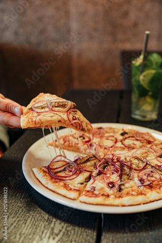 Foto Close-up of a diner lifting a hot pizza slice with stretchy melted cheese and re