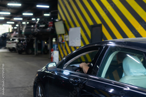 фотографія Man drives repaired automobile out of spacious repair workshop after careful and professional maintenance