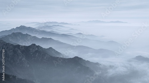 Bild auf Leinwand Misty mountain peaks receding into the distance with a thick layer of fog, seren