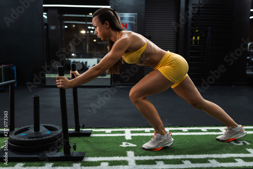 Canvastavla Woman pushing weighted sled in gym training session