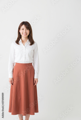 Young woman smiling in white blouse and coral skirt standing indoors