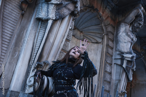 Принти на полотні Raised hand in a spell gesture, woman in a black leather harness looks up, ritua