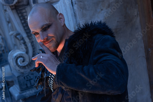 Canvastavla Man with sly smile touching his face, cunning villain character, dark alternative style