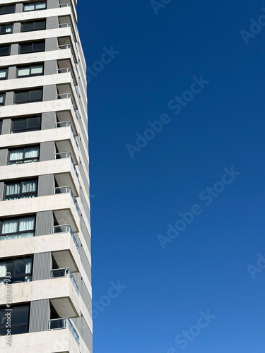 Modern apartment building facade against clear blue sky, minimalist urban architecture and graphic resources