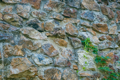 Foto Rustic stone wall built from irregular weathered rocks with gray mortar and a gr