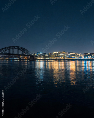 Night river reflections of city lights and bridge arch silhouette