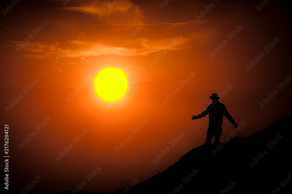 Fototapeta premium Hiker silhouette embracing freedom on mountain peak at sunset