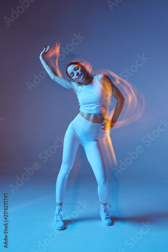 Energetic young girl sportswoman in sportswear training exercising in studio. Long exposure, motion blur. Copy space
