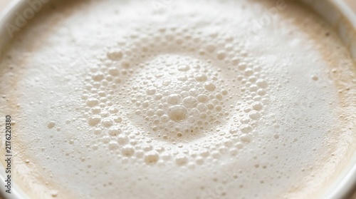Close up top view of a fresh cup of creamy cappuccino coffee with textured milk foam bubbles
