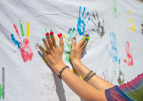 Hands with colorful paint leaving prints on a white cloth during an art event