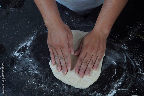 Foto Hands pressing and shaping soft yeast dough on a flour-dusted kitchen worktop during the homemade bread preparation process