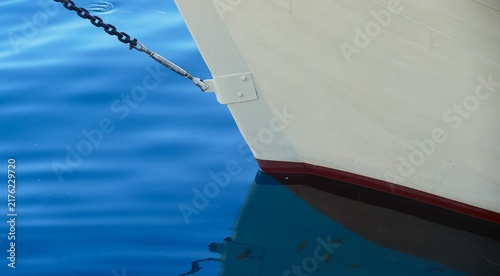 White wooden boat on the sea in harbor with reflection in water, sea transportation and nautical boat background