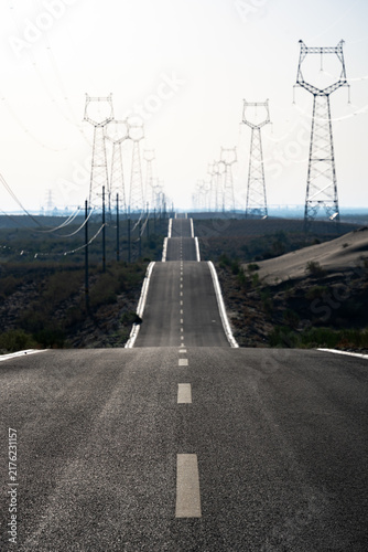 Fotografía High voltage transmission towers extending along the desert highway road