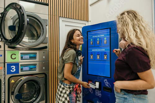 Young women friends paying for laundry services
