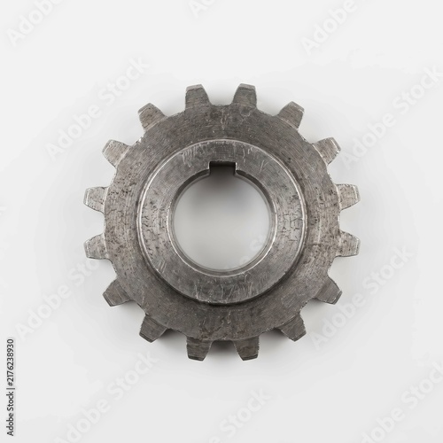 Industrial metal gear with textured surface detail captured from above on a clean white background for mechanical engineering project concepts