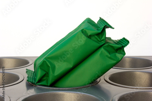 Two green blank snack wrappers on a metal muffin baking pan