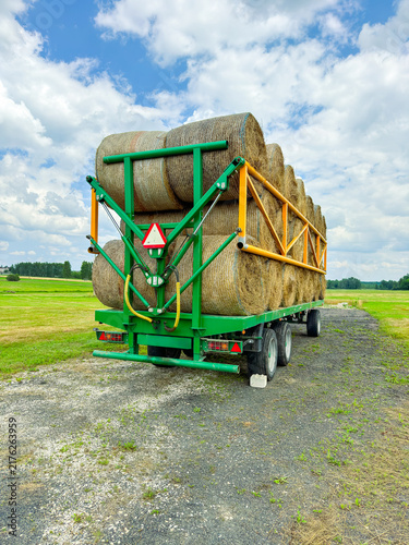 Fotografie Carrying hay bales on a trailer in a field during daytime in a rural area
