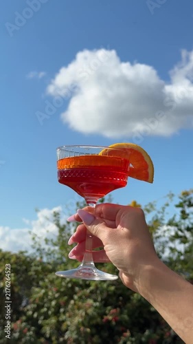 Woman Hand Holding Cocktail Glass Against Blue Sky Video