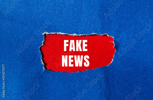 Foto Fake news message written on ripped torn paper background