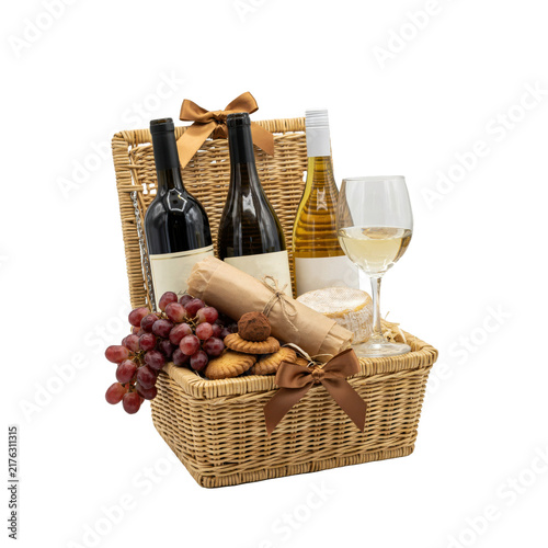 Wicker gift basket with bottles of wine, red grapes, cheese, and cookies decorated with brown satin ribbons isolated on a transparent background