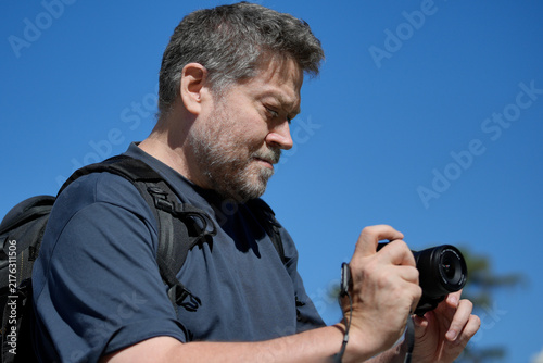 Man photographing outdoors with camera against blue sky