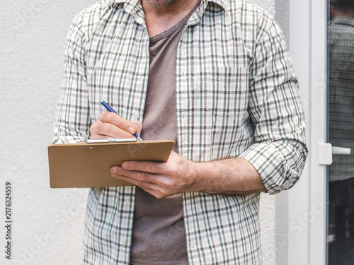 Canvas Print Man conducts a social survey outside home, writing on clipboard