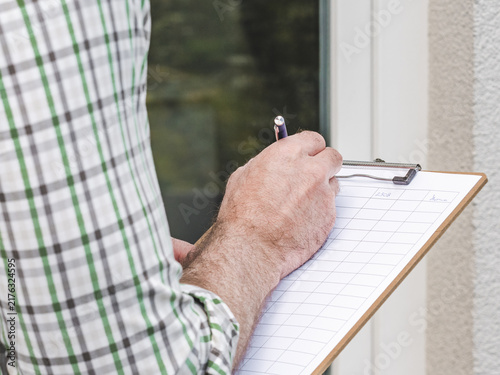 Photography Man conducts a social survey outside home, writing on clipboard