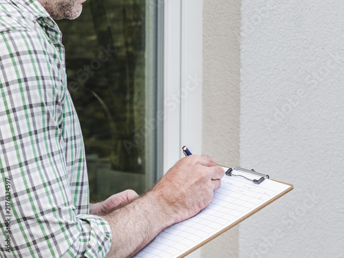 Принти на полотні Man conducts a social survey outside home, writing on clipboard