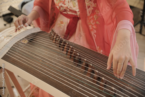 Fotografie Woman playing a traditional Indonesian string instrument, highlighting cultural music, artistic performance, and the preservation of traditional musical heritage